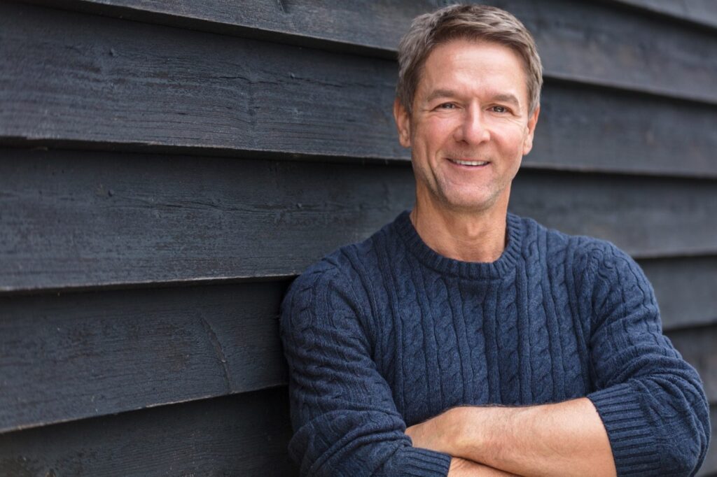 man smiling with arms crossed, looking hopeful for the future now that he has found help through counselling