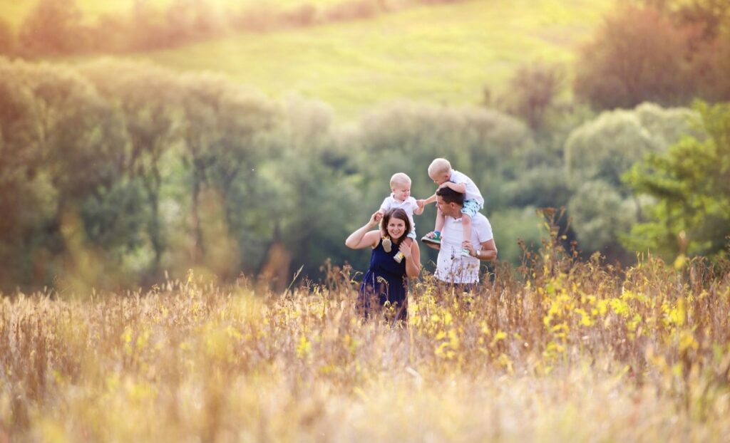 young family in a field, kids on shoulders, playing together, family staying connected